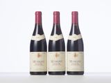 three bottles of red wine are lined up on a table