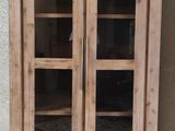 une armoire en bois avec des portes vitrées, posée sur un sol carrelé