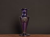 a purple glass vase sitting on a wooden table