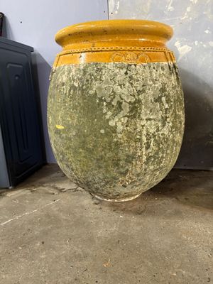 a yellow vase sitting on the floor next to a blue wall