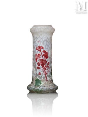 un vase en verre orné de fleurs rouges, posé sur une surface blanche