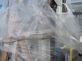 a man standing next to a machine that is wrapped in plastic
