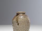 un petit vase posé sur une table, sur fond gris