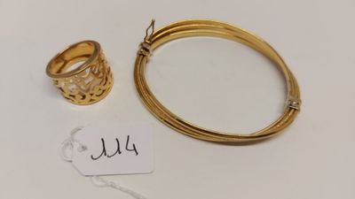 un gros plan d'un bracelet et d'une bague en or posés sur une surface blanche