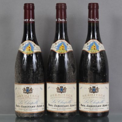 Trois bouteilles de vin sont alignées sur une table en verre