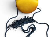 mustard colored purse with tassels on a white background