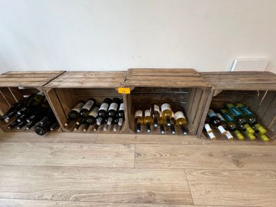 de nombreuses bouteilles de vin dans des caisses en bois posées par terre