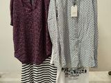 two women ' s shirts hanging on a rack in a clothing store