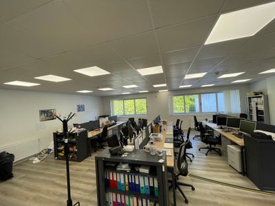 une salle où se trouvent de nombreux bureaux et chaises