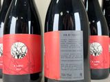 six bottles of red wine are lined up on a table