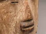 une photo en gros plan d'un masque en bois posé sur un socle