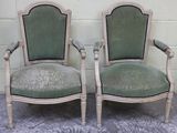 une paire de fauteuils rembourrés verts devant un mur de briques blanches