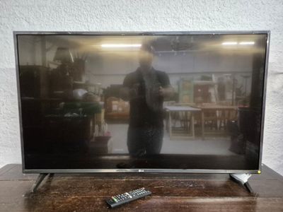 un téléviseur posé sur une table en bois, avec une télécommande dessus