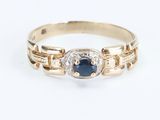 a close up of a gold ring with a sapphire and diamonds