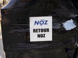une affiche « noz » à l'arrière d'une poubelle noire