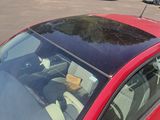 a red car parked in a parking lot with other cars in the background