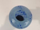 a blue vase with a black base on a white table
