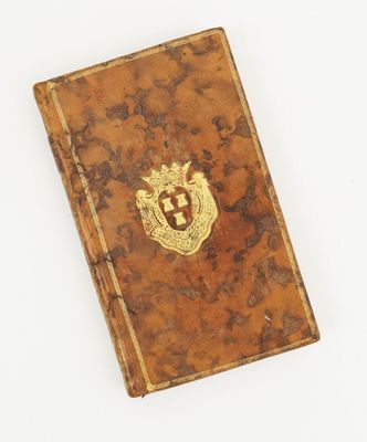 un vieux livre orné d'un emblème doré, posé sur une surface blanche