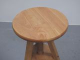 a small wooden stool with a wooden seat on a cement floor