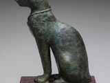 a bronze statue of a cat sitting on top of a base