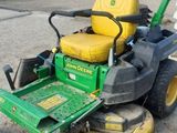 a picture of a green lawn mower parked in a parking lot