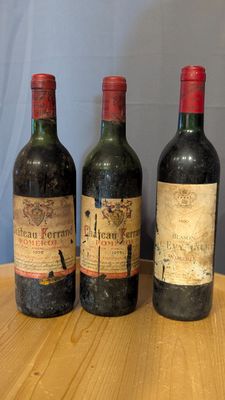 three bottles of wine sit on a wooden table in front of a blue wall