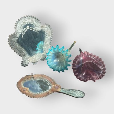 Plusieurs objets en verre de différentes couleurs sont disposés sur une surface blanche.