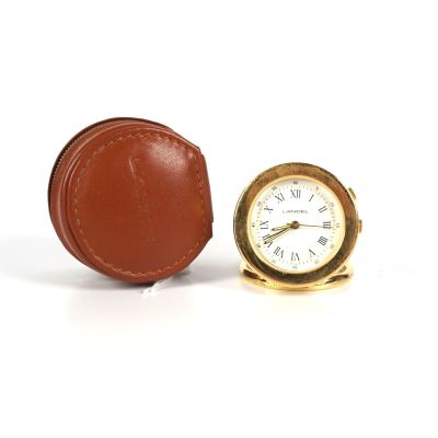 une petite horloge posée à côté d'un étui en cuir