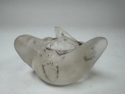 a glass vase with a bird on it on a white surface