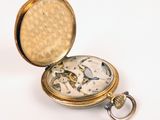 a gold pocket watch sitting on a white surface