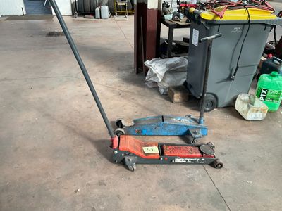 a red and black jack sitting on the floor in a garage