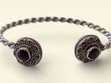 un gros plan d'un bracelet en argent orné d'une pierre rouge