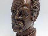 bronze bust of a man with curly hair and a beard