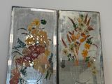 two mirrors that have flowers on them on a shelf