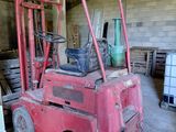 un chariot élévateur rouge dans un bâtiment où se trouvent de nombreuses palettes