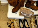 several pairs of shoes are lined up on a shelf next to a purse