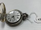 a silver pocket watch with roman numerals on it