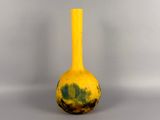 a yellow vase sitting on a table with a gray background