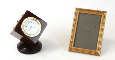 un petit cadre photo à côté d'une petite horloge posée sur un support