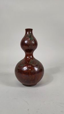 un vase brun posé sur une surface blanche