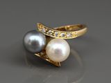 un gros plan d'une bague en perle et diamant posée sur une table