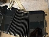 a black accordion sitting on the floor next to a bag