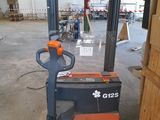 an orange and black forklift sitting in a warehouse next to a wooden door