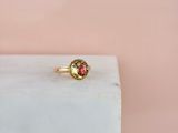 une bague en or sertie d'une pierre rouge, posée sur un bloc de marbre