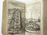 someone is holding an open book with a drawing of a city in it