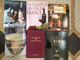 plusieurs livres posés sur une table, à côté d'une bouteille de vin et d'un verre