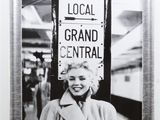 black and white photograph of a woman standing in front of a sign