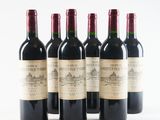 six bottles of wine are lined up in a row on a white surface
