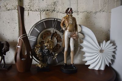 a statue of a man standing next to a clock and a vase on a table