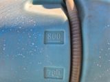 un gros plan d'un tuyau raccordé à un réservoir bleu